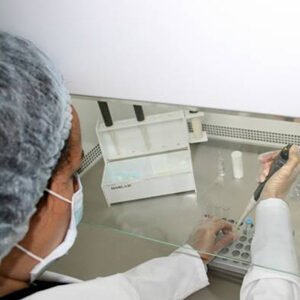 Técnica de laboratorio pipeteando bajo cabina de flujo laminar